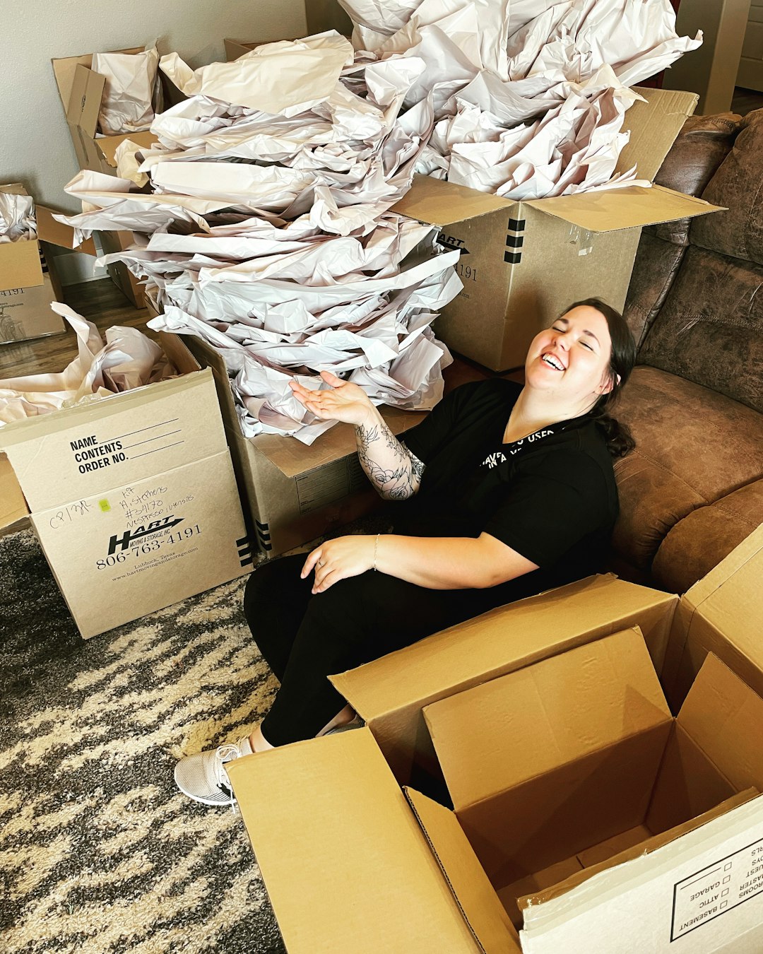 A woman laughing among moving boxes